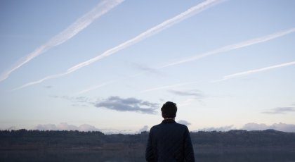 En mann ser opp på himmelen med mange flystriper. I PROSJEKTET AVIATE SKAL FOLKET HJELPE TIL Å TA BILDER AV KONDENSSTRIPER FRA FLY. 