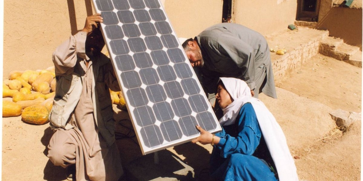 Fotografi av en kvinnelig AFGHANSK BARFOTINGENIØR som INSTALLERER SOLCELLEPANEL SAMMEN MED EKTEMANN OG NABO. 