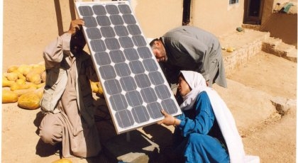 Fotografi av en kvinnelig AFGHANSK BARFOTINGENIØR som INSTALLERER SOLCELLEPANEL SAMMEN MED EKTEMANN OG NABO. 