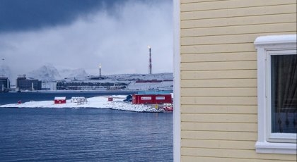 Husvegg foran kaldt industrilandskap i Finnmark.